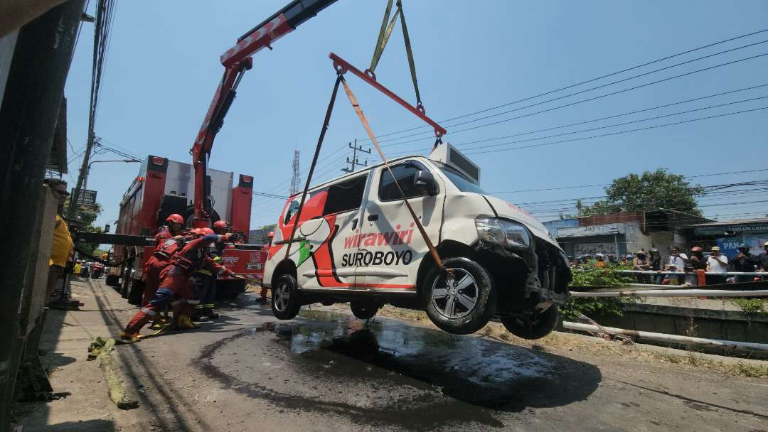 Angkutan feeder Wira-Wiri Surabaya FD03 rute Terminal Intermoda Joyoboyo (TIJ)-Gunung Anyar, yang tercebur ke sungai di kawasan Jalan Medokan Sawah, Rungkut. (Foto: Julianus Palermo/Ngopibareng.id)