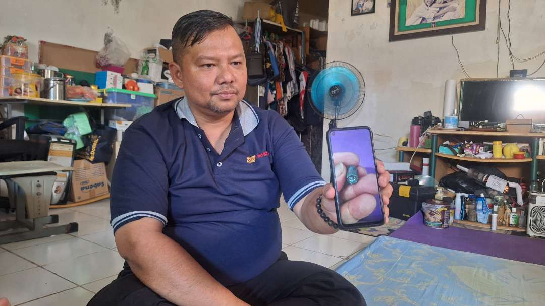 Ucok Sibarani, suami korban peluru nyasar, menunjukkan foto proyektil yang mengenai paha istrinya saat sedang tertidur di kamarnya, Sabtu 21 September 2024. (Foto: Julianus Palermo/Ngopibareng.id)