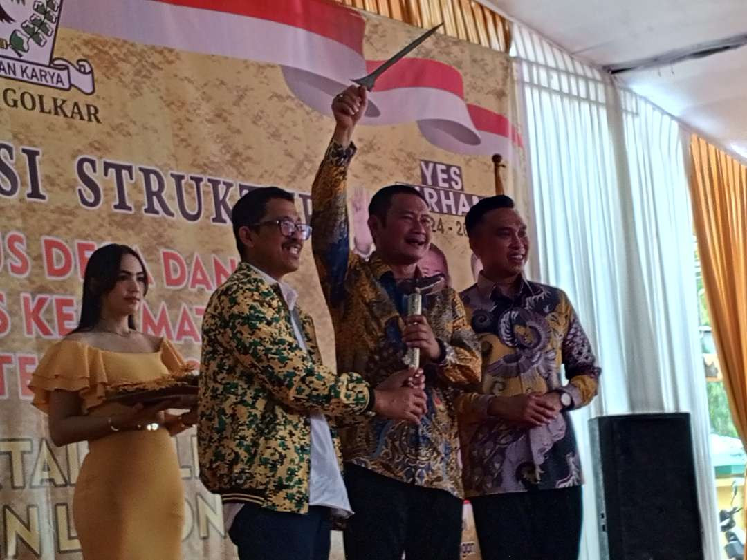 Yuhronur Efendi didampingi Dirham Akbar Aksara mengacungkan keris hadiah dari Ketua DPD Partai Golkar Lamongan Kacung Purwanto (Foto: Imron Rosidi/Ngopibareng.id)