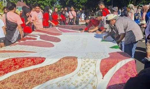 Tiga ratus siswa di Bondowoso membatik bersama pada kain panjang 40 meter membentang di jalan sekitar Monumen Gerbong Maut, Minggu 29 September 2024. (Foto: Guido Saphan/Ngopibareng id)