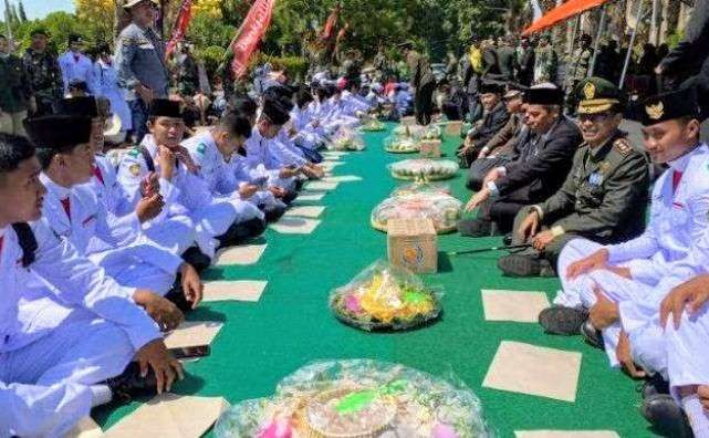 Dandim 0822/Bondowoso Letkol Arh Achmad Yani dan anggora TNI duduk lesehan makan bersama rakyat sebanyak 200 nasi tumpeng. (Foto: Guido Saphan/Ngopibareng.id)