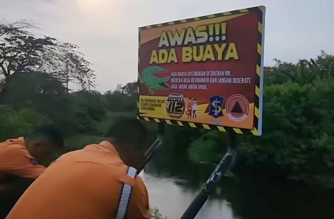 Petugas BPBD Kota Surabaya saat memasang papan berisi imbauan kepada masyarakat untuk mewaspadai kehadiran buaya di sungai dekat kampus UINSA. (Foto: BPBD Kota Surabaya)