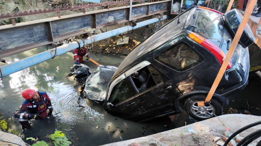 Petugas melakukan proses evakuasi pengangkatan kendaraan yang masuk kali di Jalan Mulyorejo, Surabaya, Rabu 9 Oktober 2024. (Foto: Fariz Yarbo/Ngopibareng.id)