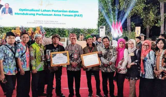 Kepala Dispertapang Bondowoso, Hendri Widotono (tengah) memperlihatkan dua piagam penghargaan Awards Peduli Ketahanan Pangan Jatim 2024. (Foto: Dispertapang Bondowoso)