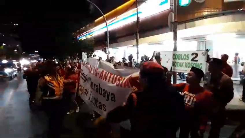 Massa pendukung Eri-Armuji saat berusaha untuk menutup-nutupi spanduk yang dibentangkan massa aksi "Gerakan Coblos Kotak Kosong", di tengah debat publik pertama Pilwali Surabaya 2024, di Jalan Basuki Rahmat, Genteng, Rabu 16 Oktober 2024 malam. (Foto: Julianus Palermo/Ngopibareng.id)