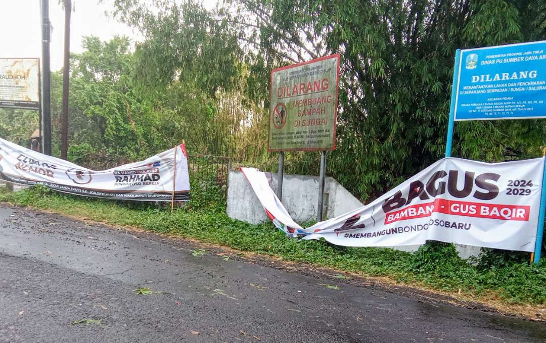 APK spanduk paslon 1 Ra Hamid-Ra As,'ad dan paslon 2 Bambang-Gus Baqir difasilitasi KPU terpasang tak layak di pinggir jalan dekat Jembatan Pejaten. (Foto: Guido Saphan/Ngopibareng.id)