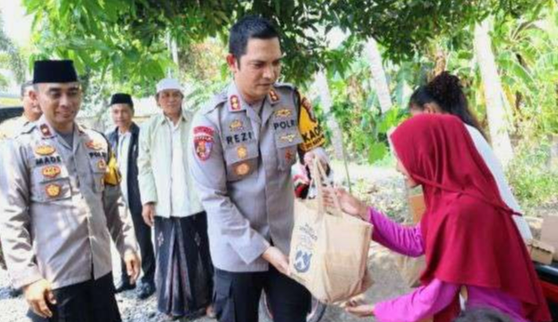 Warga kurang mampu menerima bantuan paket sembako Hari Jadi ke-73 Humas Polri diserahkan langsung Kapolres Situbondo, AKBP Rezi Dharmawan.(Foto: Guido/Ngopibareng.id)