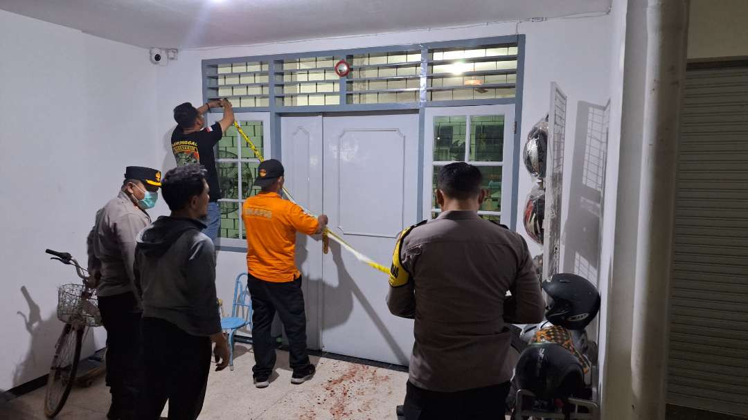 Pihak kepolisian memasang garis polisi di pintu rumah, tempat kejadian perkara pembacokan di Jalan Putat Indah Tengah I Nomor 8, Kelurahan Putat Gede, Kecamatan Sukomanunggal, Surabaya. (Foto: Julianus Palermo/Ngopibareng.id)