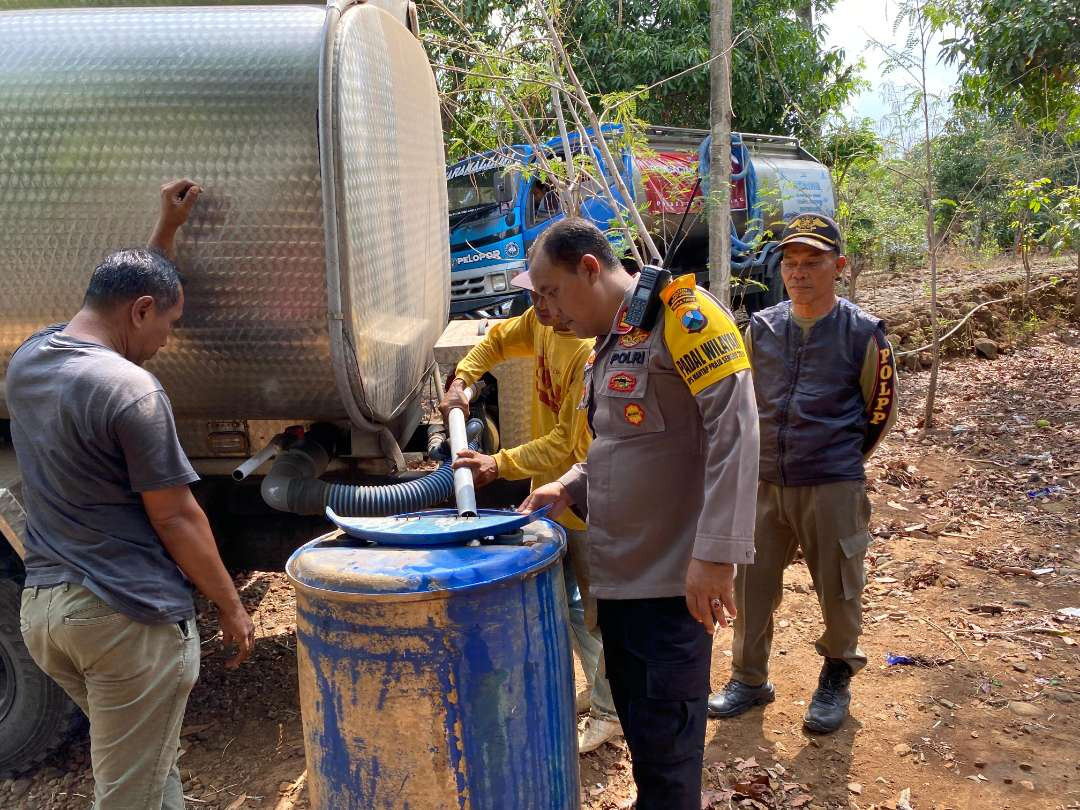 Kapolsek Wongsorejo memindahkan air dari tangki ke tandon milik warga (Foto : istimewa)