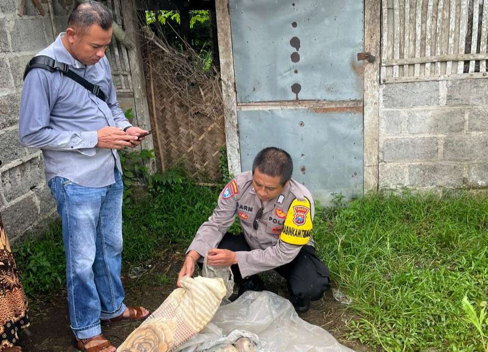 Polisi saat mengecek bungkusan plastik berisi mayat bayi. (Foto: Dokumentasi Polsek Balung)