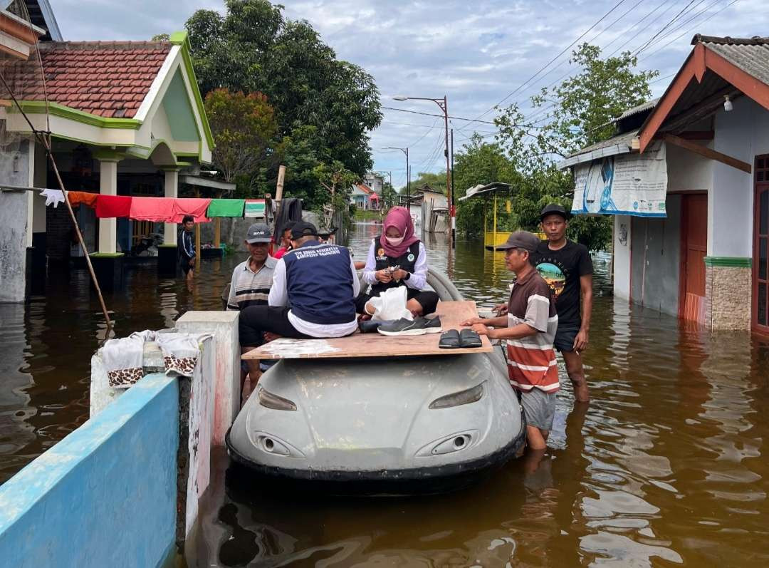 Tim nakes keliling pakai perahu bantu warga terdampak banjir.(Foto Deni Lukmantara/Ngopibareng.id)