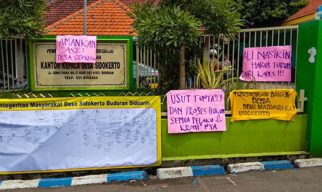 Spanduk kekesalan warga di depan Kantor Balai Desa Sidokerto (Foto: Aini/Ngopibareng.id)