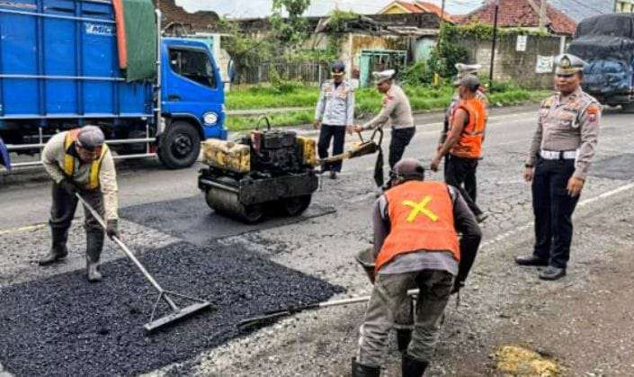 Anggota Satlantas Polres Situbondo bersama Dinas PU menambal jalan berlubang Jalur Pantura Situbondo menjelang Nataru. (Foto: Guido/Ngopibareng.id)