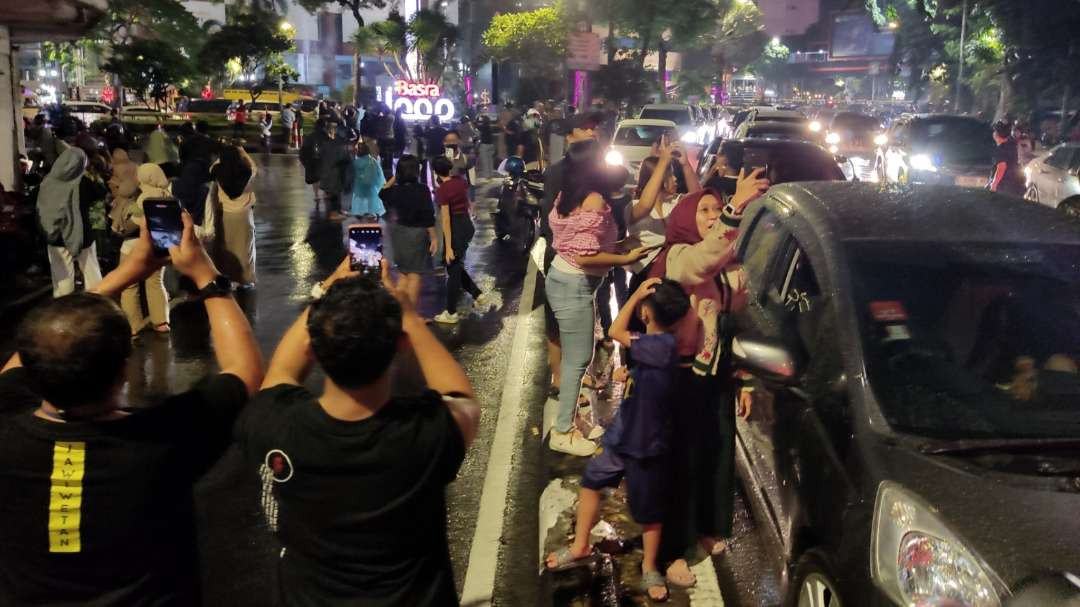 Masyarakat saat mengabadikan momen pesta kembang api pada malam Tahun Baru 2025 di Jalan Gubernur Suryo, Surabaya, Rabu 1 Januari 2025. (Foto: Fariz Yarbo/Ngopibareng.id)