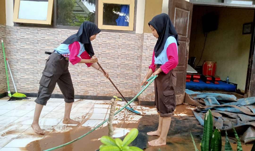 Sejumlah siswi atau pengurus Osis SMPN 1 Rengel Kabupaten Tuban membersihkan lumpur sisa banjir bandang. (Foto: Khoirul Huda/Ngopibareng.id)