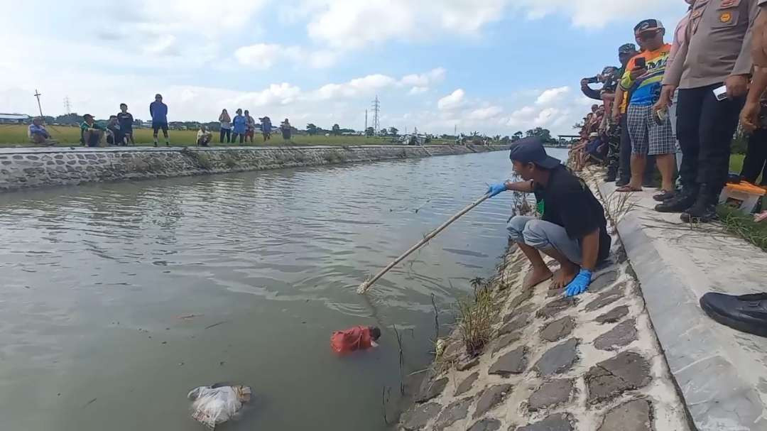 Warga saat mencoba mengevakuasi tas kresek merah yang ternyata berisi bayi. (Foto" Tova Pradana?Ngopibareng.id