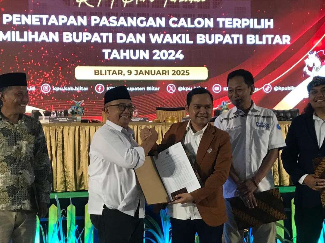 Ketua KPUD Kabupaten Blitar, Sugino menyerahkan Berita Acara dan Surat Keputusan Penetapan Rijanto dan Becky Herdiansyah Bupati dan Wakil Bupati 2025-2030. (Foto: Choirul Anam/Ngopibareng.id)