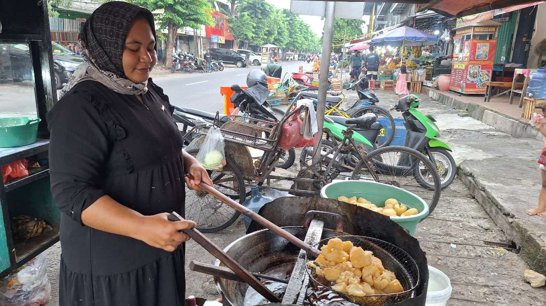 Salah seorang pedagang kaki lima gorengan di Pasar Pucang Surabaya, Musrifah, saat memasak adonan gorengan miliknya, Selasa 14 Januari 2025. (Foto: Julianus Palermo/Ngopibareng.id)