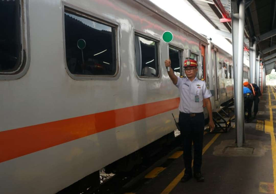 Petugas stasiun memberikan aba-aba pemberangkatan kereta api (foto : istimewa)