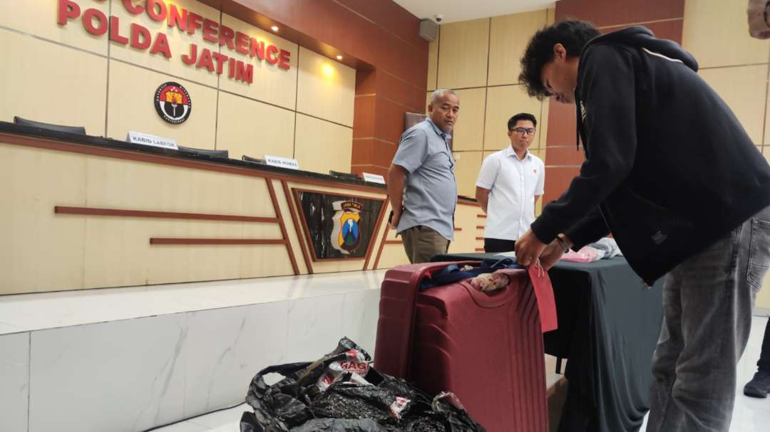 Aparat mengamankan barang bukti koper merah yang sebelumnya berisi mayat koban. (Foto: Fariz Yarbo/Ngopibareng.id)