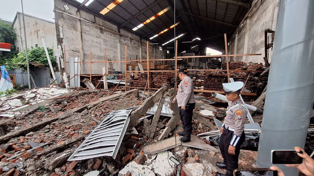 Petugas kepolisian saat melakukan olah TKP atas kejadian rubuhnya toko bangunan, di dekat SPBU Jalan Tanjung Sari, Sukomanunggal, Surabaya, Kamis 13 Februari 2025. (Foto: Julianus Palermo/Ngopibareng.id)
