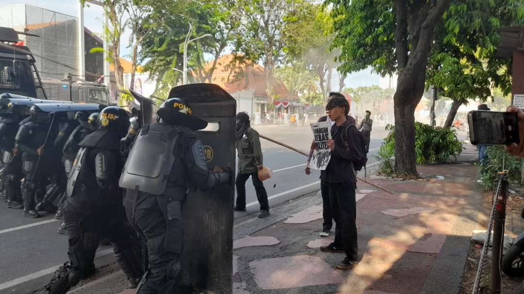 Seorang pengunjukrasa membentangkan poster agar dibaca polisi saat aksi di depan Grahadi. (Foto: Yunus Ar Rahman/Ngopibareng.id)