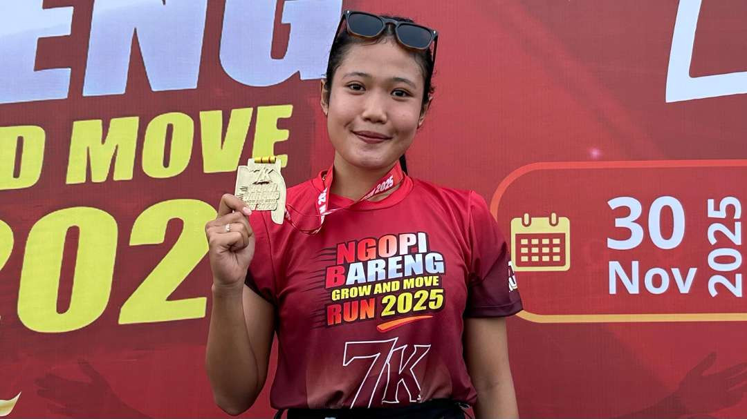 Salah satu pelari yang memegang medali finisher berbentuk N dan jersey Ngopibareng Grow and Move Run 2025. (Foto: Putra Pradana/Ngopibareng.id)