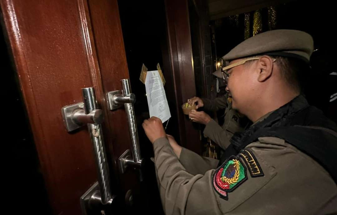 Petugas Satpol PP memasang surat edaran di salah satu tempat usaha. (Foto: Istimewa)