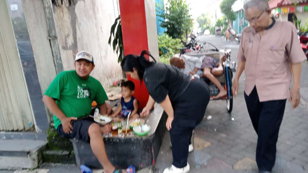 Makan soto sambil ngelesot di pinggir trotoar bagi pelanggan Soto Cak Busro tidak masalah, yang penting nikmat dan senang di hati.  (Foto: Asmanu Sudarso/Ngopibarwng.id)